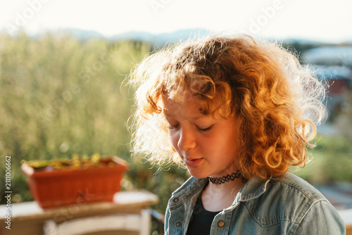 Foto Teen girl with curly hair stands outdoors with a pensive expression