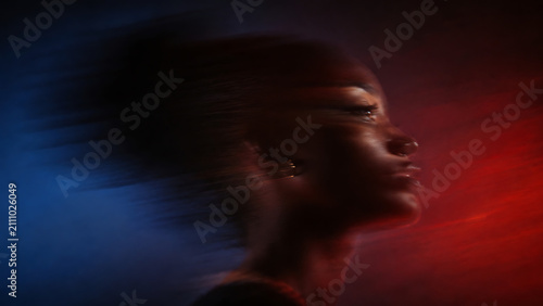 Dramatic portrait of a young woman with motion blur and vibrant red and blue lighting
