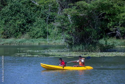 A father and son paddle a kayak on Thalkote Lake at Sigiriya in Sri Lanka.