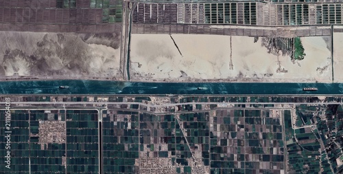 Billede på lærred Aerial view of extensive fish farm ponds along the Suez Canal near Port Said Egypt with three cargo vessels moving through the channel
