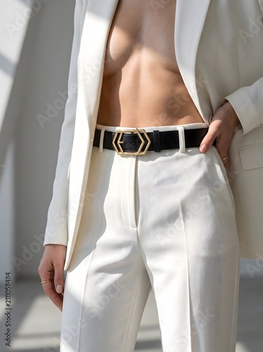 Elegant woman in white pantsuit showing bare torso, accessorized with stylish black belt and gold buckle.