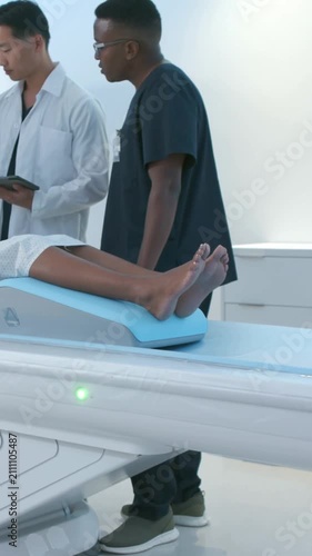 Vertical video: Referencing tablet doc lab coat, tech scrubs adjusting paper on scan bed wedge prep