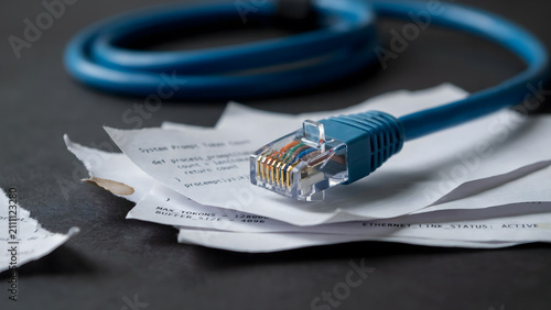 A blue ethernet patch cable resting on a stack of white office paper documents