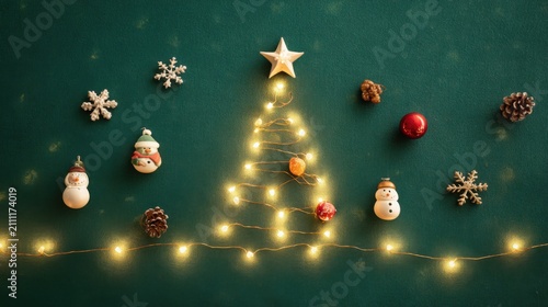 Top-down flat lay Christmas scene on a deep green background, warm yellow fairy lights arranged in the shape of a Christmas tree