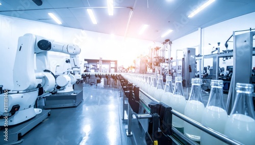 Automated production line in a modern factory with robotic arms and conveyor belt carrying bottled beverages.