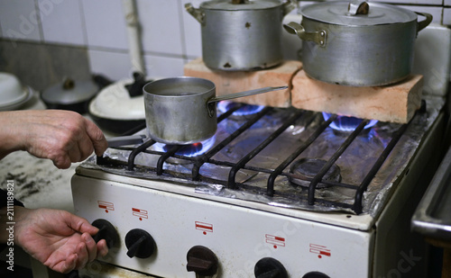 Canvas Print Cold kitchen with brick on stove heating metal pots, brick used for warmth, surv