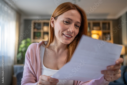 Fotografie Woman reading letter with happy smiling expression at home