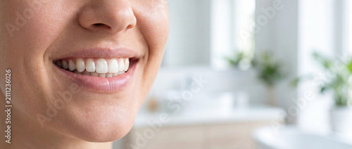 Healthy smile showing clean white teeth in a bright close-up macro shot with natural skin tones and a soft bathroom background, ideal for dental hygiene and cosmetic whitening ads