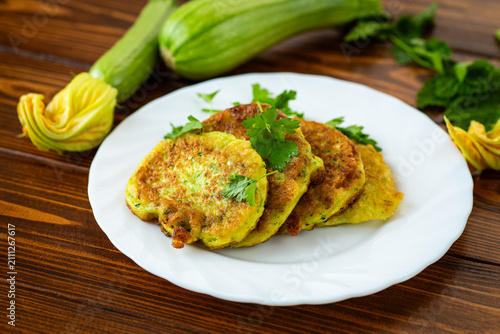 Fotografie Healthy zucchini pancakes with parsley garnish on white plate
