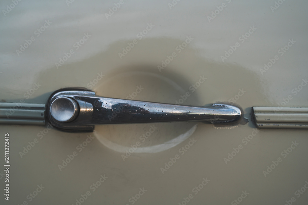 Obraz premium Worn and scratched door handle with push button on a classic retro car, close up detail