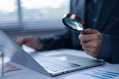 Canvastavla Business professional using a magnifying glass while working on a laptop, repres