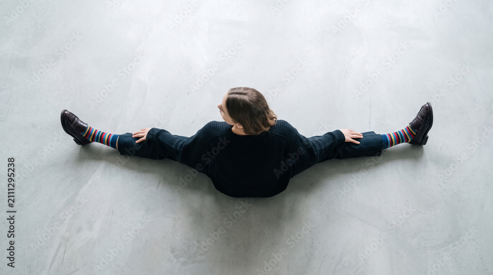 Obraz premium Woman doing a split on a light gray floor, showcasing flexibility, comfort, and unique colorful socks