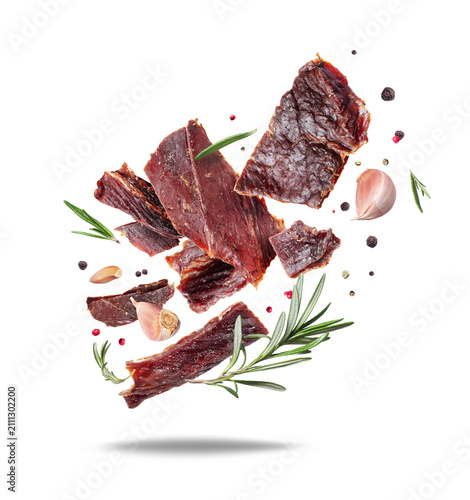 Canvas Print Delicious beef jerky with rosemary and garlic in the air isolated on a white bac