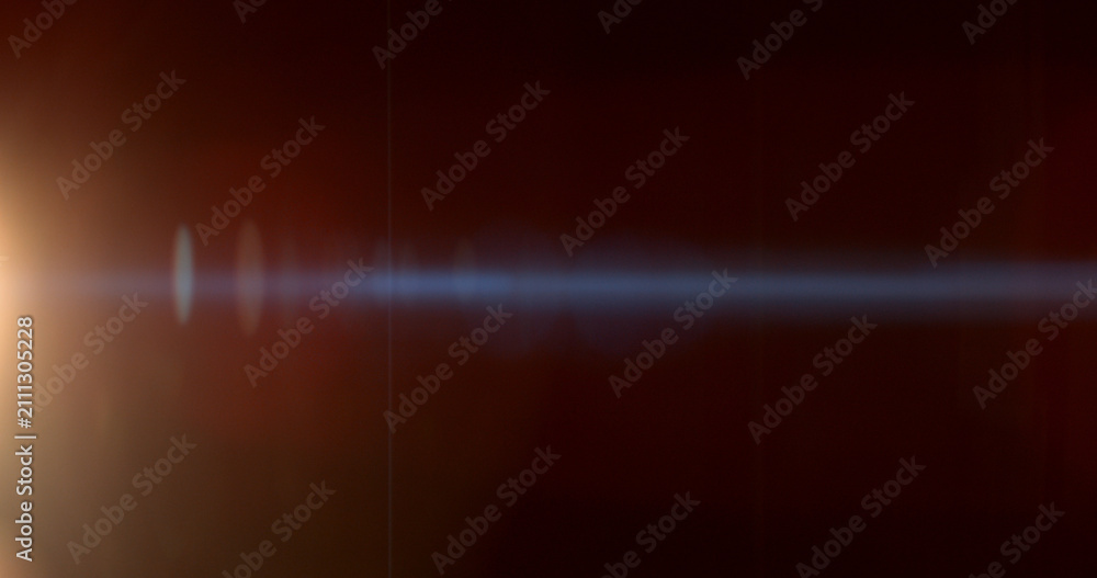 Obraz premium Warm anamorphic lens flare overlay featuring a golden light source, blue horizontal light streak, realistic optical reflections and subtle glow on a black background. Premium VFX asset.