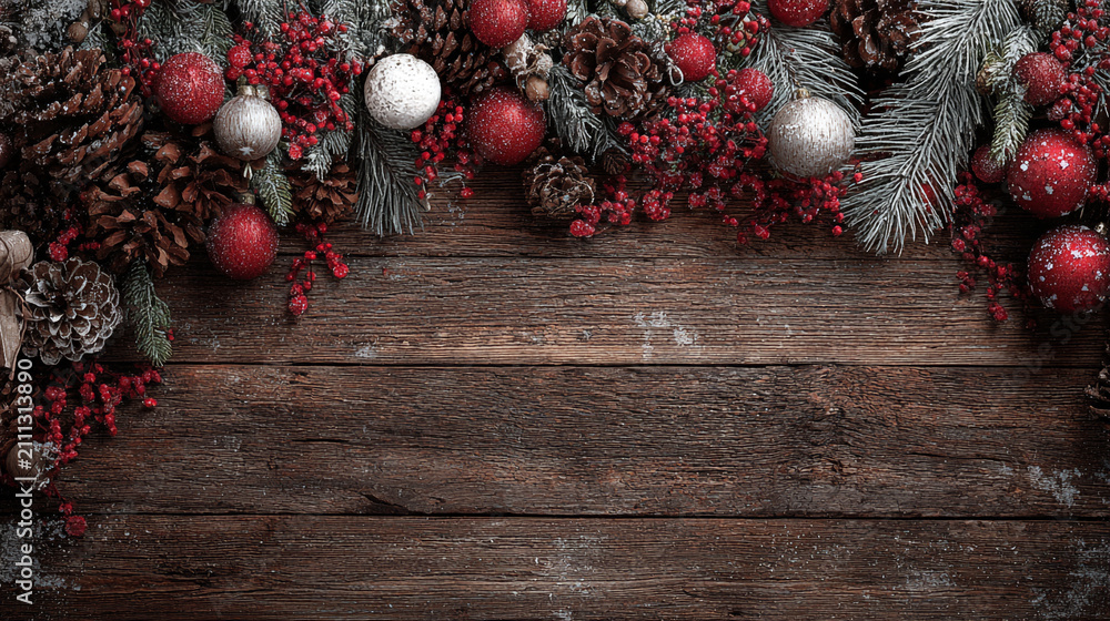 Obraz premium Festive Christmas background on dark wood featuring pine branches, cones, candy canes, red berries, angel wings, and gifts at top with copy space. 
