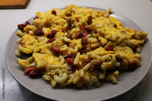 View of a plate with prepared food, pasta with pieces of sausage fried with egg

