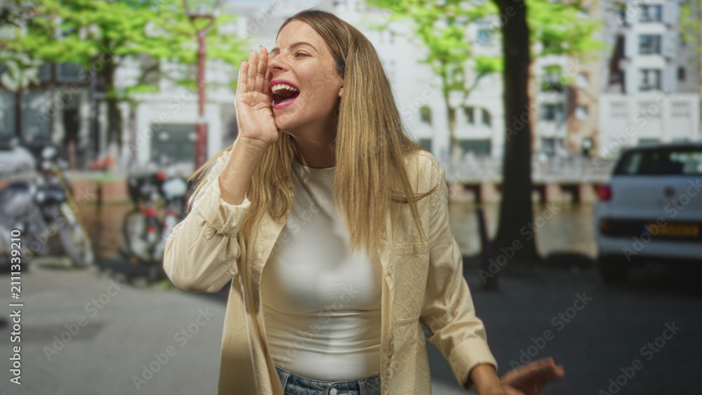 Fototapeta premium Woman cups hand to mouth shouting on a city street with parked bicycles and cars, wearing a casual shirt and denim jeans; joyful expression.
