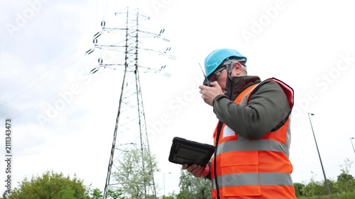 Male electrical engineer working near a high-voltage power line. Technician or power inspector inspects the power grid infrastructure.