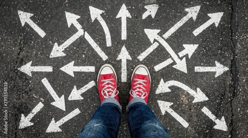 Person wearing red sneakers on asphalt surrounded by chaotic multi directional arrows