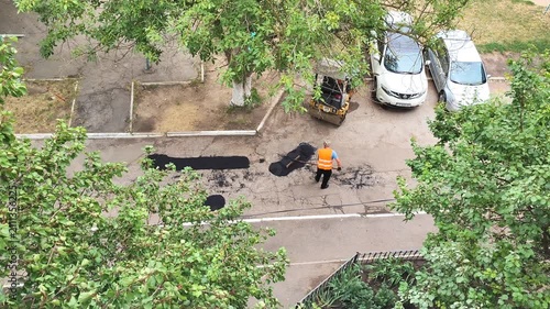 Construction site overhead view, workers with safety vests and road repair equipment on street, aerial infrastructure maintenance.