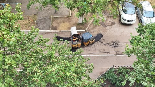  Road compacting equipment with worker from aerial view, construction maintenance of street asphalt, urban infrastructure work.