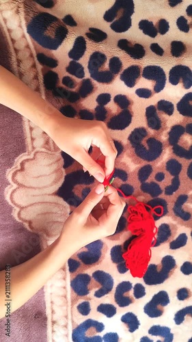  Person holding red yarn for knitting and crochet craft, hands working with fiber thread, handmade hobby.