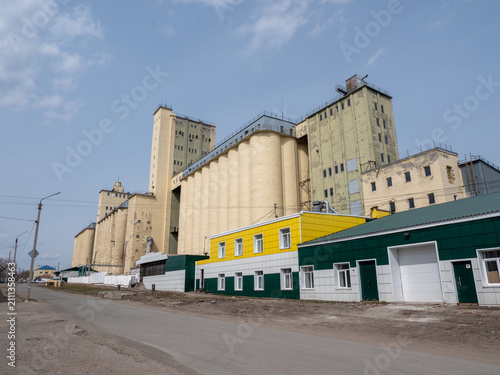 Large concrete grain elevator building against a clear blue sky, industrial agricultural storage facility for grain processing and farming