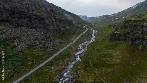 Фотография Aerial landscape of green mountain valley, rocky slopes and a narrow river beside a road in Norway