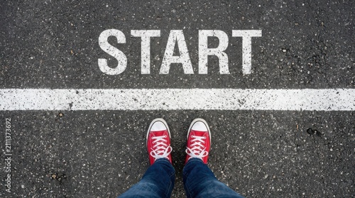 Person standing at a starting line on an asphalt road with the word start written