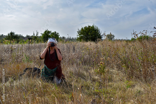 An elderly woman takes a break from work and takes a camera to capture the landscape.