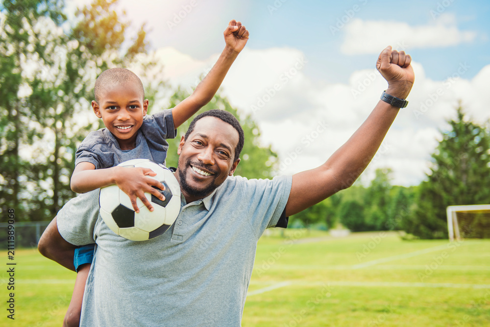 Obraz premium father with son playing football or soccer outside on field