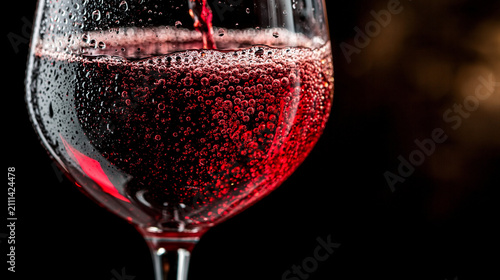 Close up , put the red wine is in the wine glass , black background.