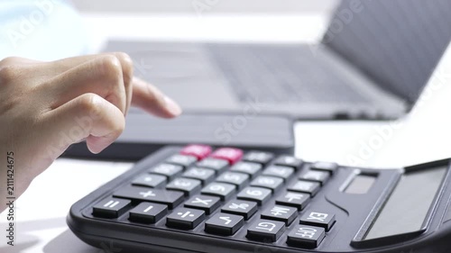 Closeup finger pressing calculator key on office laptop, hand entering number for finance and work, calculator keypad in background with soft light, searchable SEO title