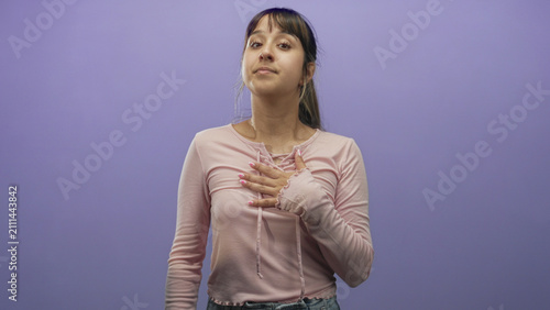 Foto Young woman with hand raised and hand on chest in studio pledging with eyes closed wearing pink top; sincerity commitment