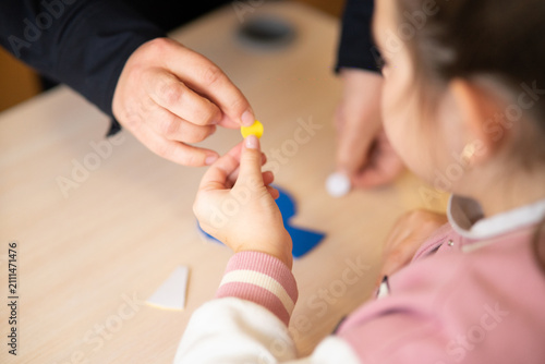 Adult giving small yellow craft piece to child