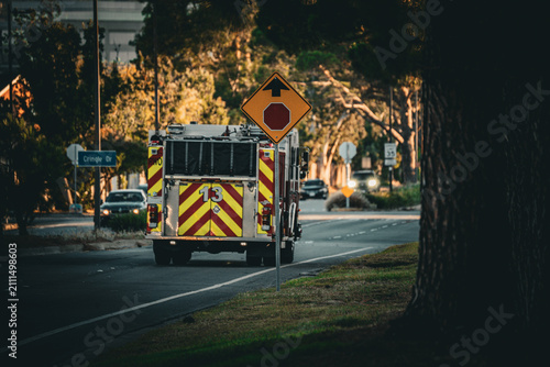 Konstfotografi Fire truck with reflective stripes driving on a road near trees