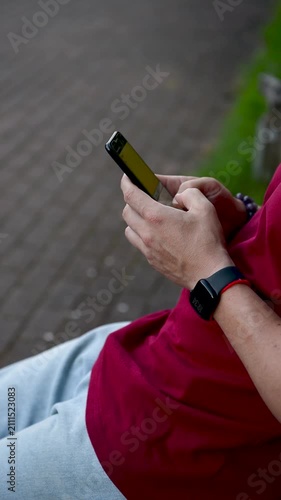 Close-up of hands typing on a phone. Close up view of hands holding modern smartphone, with thumbs actively typing message, browsing social media, or scrolling through news feed in a well lit indoor s