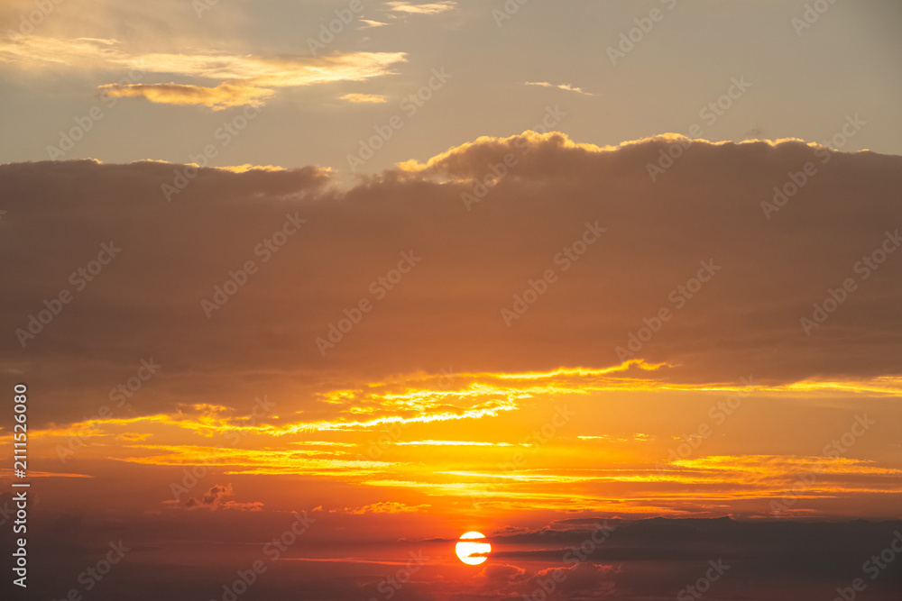 Fototapeta premium Bright sunset with orange clouds and sun on the horizon