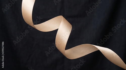 Elegant Rose Gold Satin Ribbon Curving Gracefully Against a Dark Black Backdrop