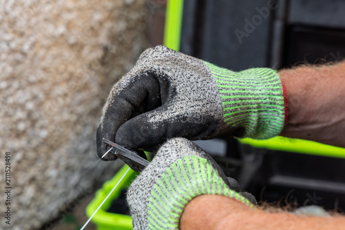 Fotografie Telecoms engineer stripping outer sheath from fibre optic cable with buffer stri