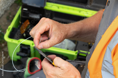 Telecoms engineer stripping blue primary coating from bare glass fibre before fusion splicing