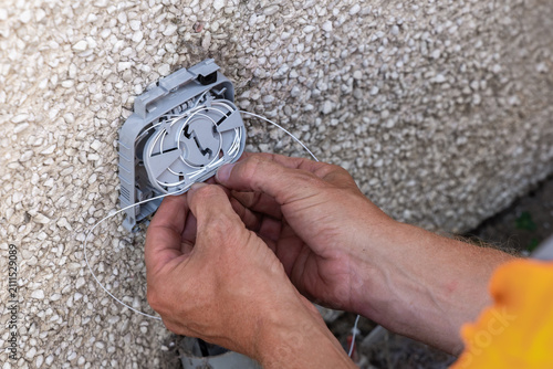 Fotografía Telecoms engineer coiling spliced fibre into exterior wall entry bracket splice
