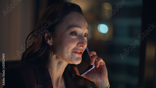 Calling woman manager working late talking positively at night office portrait