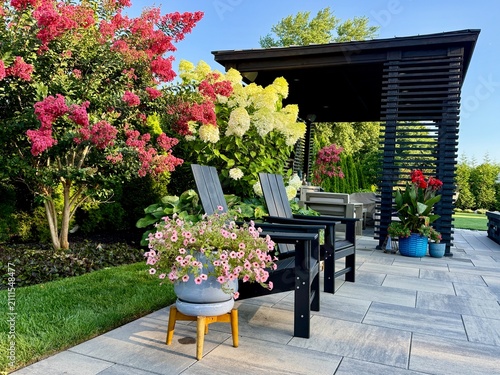 Konstfotografi Gorgeous country cottage style border garden in among a modern, sleek, luxury outdoor patio living space equipped with a pavilion, pergola, cabana, pool, chaise lounge, fire pit, hot tub, sofa