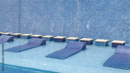 Cuadro en lienzo Luxury submerged pool loungers in shallow swimming pool at modern resort