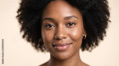 Close up portrait of a beautiful young woman with natural afro hair smiling.