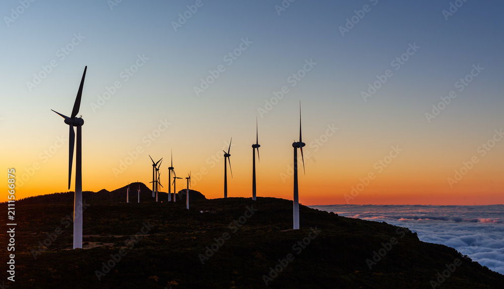 Obraz premium Wind turbines at sunset on a hillside in Bica da Cana. The wind farm generates renewable energy. Scenic view of the coastline and ocean. Located on the island of Madeira in Portugal.