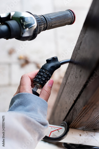 Fotografie A vertical close-up view shows a person unlocking a combination cable lock on a bicycle