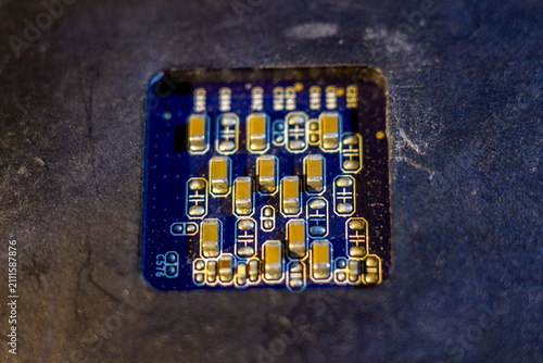 Fotografie Microscopic view of electronic circuit board components with gold capacitors on