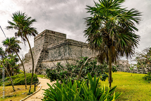 Fotografie Ancient Maya stone ruins surrounded by tropical vegetation at the Tulum Archaeological Zone in Quintana Roo, Mexico